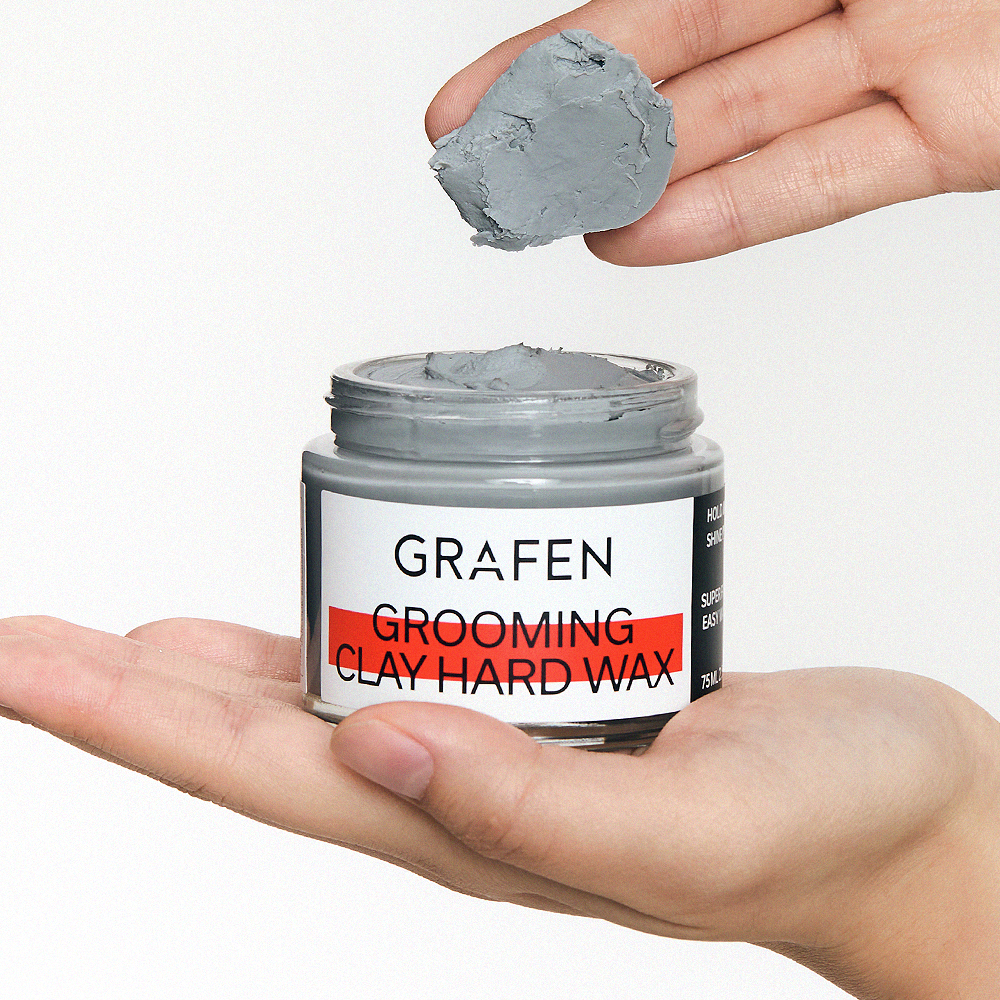 GRAFEN  Grooming Clay Hard Wax 75ml : pot de cire coiffante dans la main, texture argile grise, fond clair.