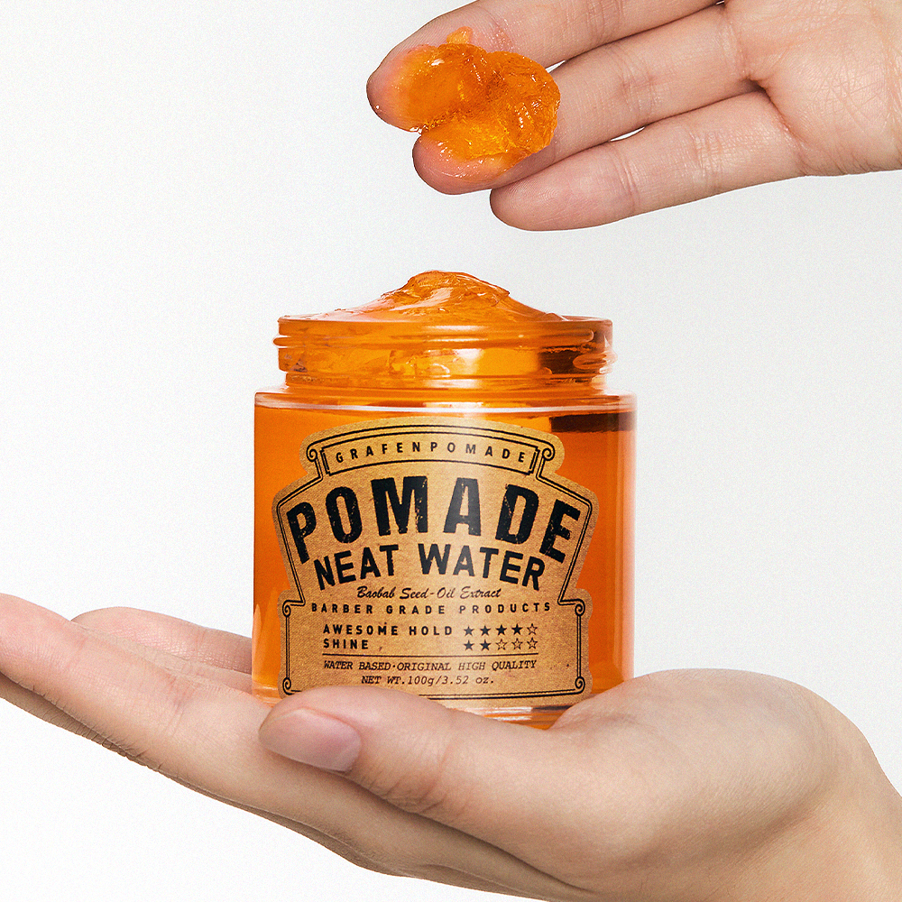 GRAFEN  Pomande Neat Water 100g : pot cosmétique orange tenu en main, avec une pommade brillante sur les doigts, fond clair.