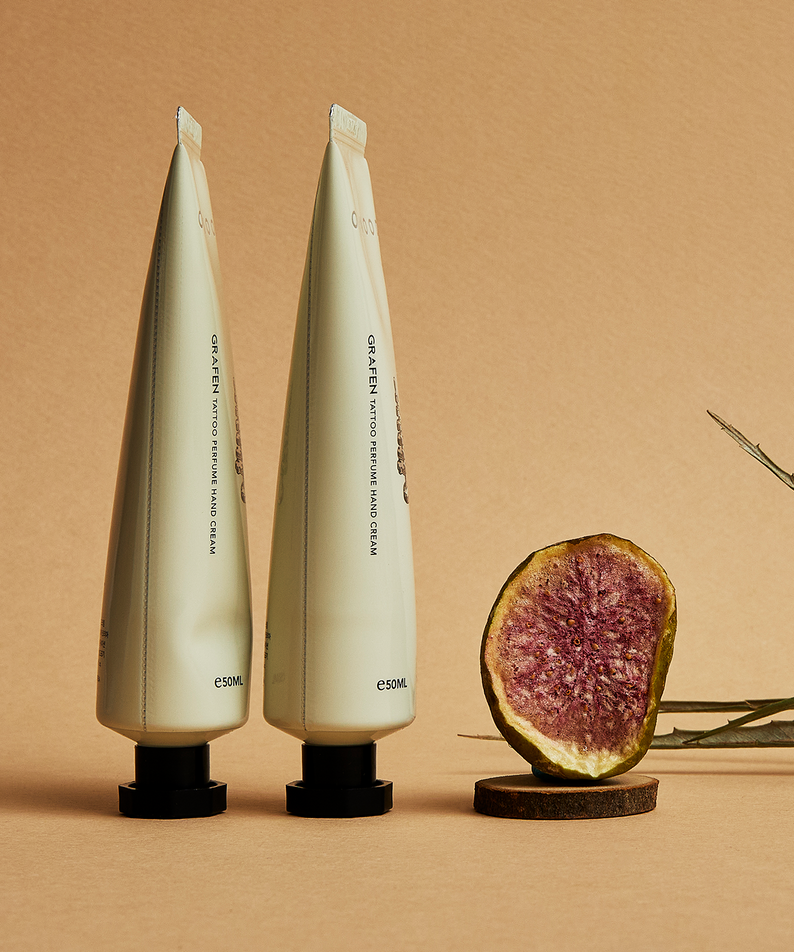 GRAFEN  Tattoo Perfume™ One Wood Hand Cream 50ml : crème mains sur fond beige, tubes près d’un fruit et brindille.