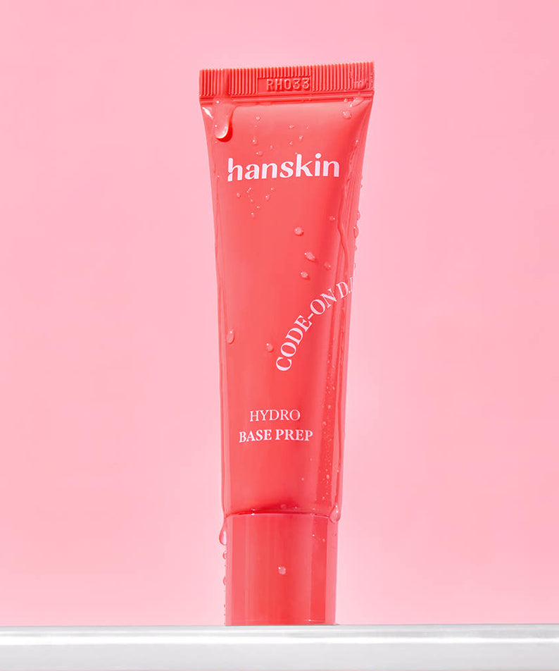 HANSKIN Code On DD Hydro Base Prep 30ml, tube rouge sur fond rose, gouttes et ambiance skincare.