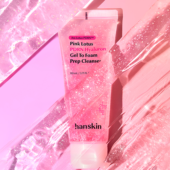 Décris l'image en français en mentionnant le produit, la marque et le contexte visuel : HANSKIN Pink Lotus PDRN Hyaluron Gel to Foam Prep Cleanser 110ml, flacon rose pailleté sur fond rose.