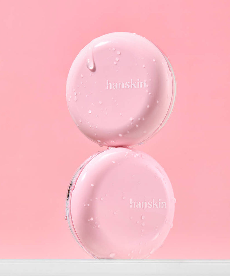HANSKIN Pink Moisturizing Tone-Up Sun Cushion 8g, produit crème rose sur fond rose, gouttes de texture, marque visible