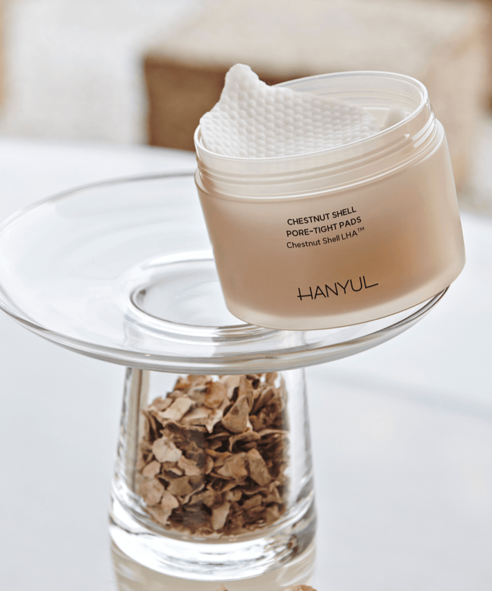 HANYUL Buddleberry Pore Tightening Pad sur une table avec un support en verre, montrant la texture des tampons pour resserrer les pores.