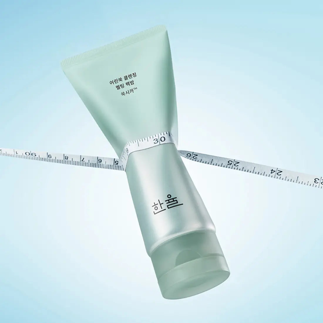 HANYUL Young Artemisia Cleansing Pack Balm 100g, tube vert sur fond bleu, ruban à mesurer visible.