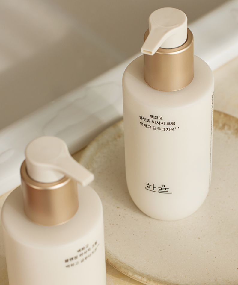 Flacon de HANYUL Baekhwago Cleansing Massage Cream 200ml sur une surface en pierre beige dans une salle de bain. Crème douce et hydratante.