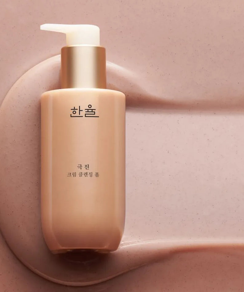 Flacon de HANYUL Extreme Cream Cleansing Foam 200ml posé sur une surface rose poudrée.