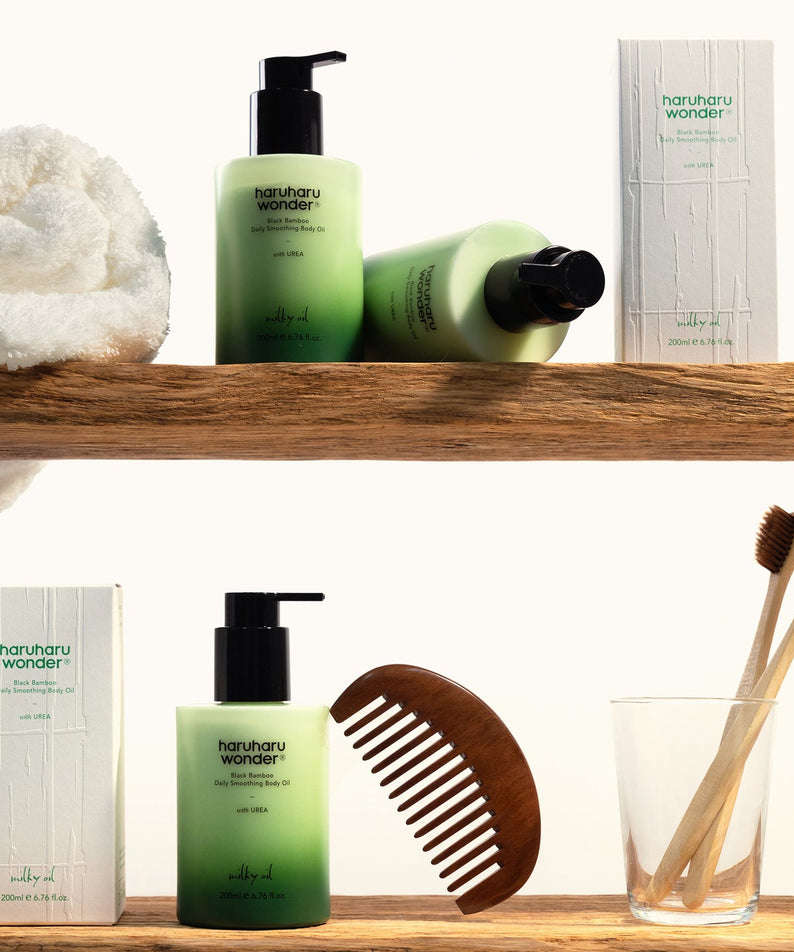 Décris l'image en français : HARUHARU Black Bamboo Daily Smoothing Body Oil 200ml de la marque, sur étagère avec accessoires.