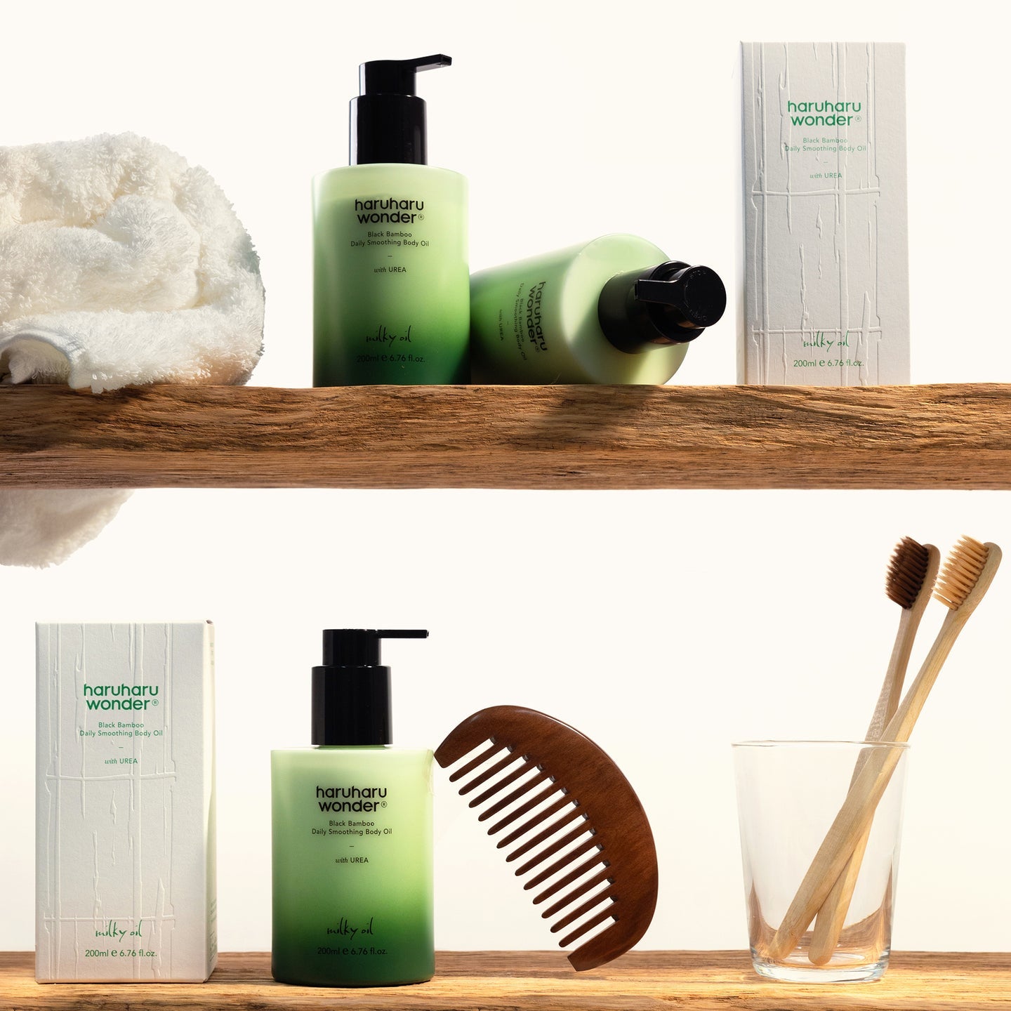 Décris l'image en français : HARUHARU Black Bamboo Daily Smoothing Body Oil 200ml de la marque, sur étagère avec accessoires.