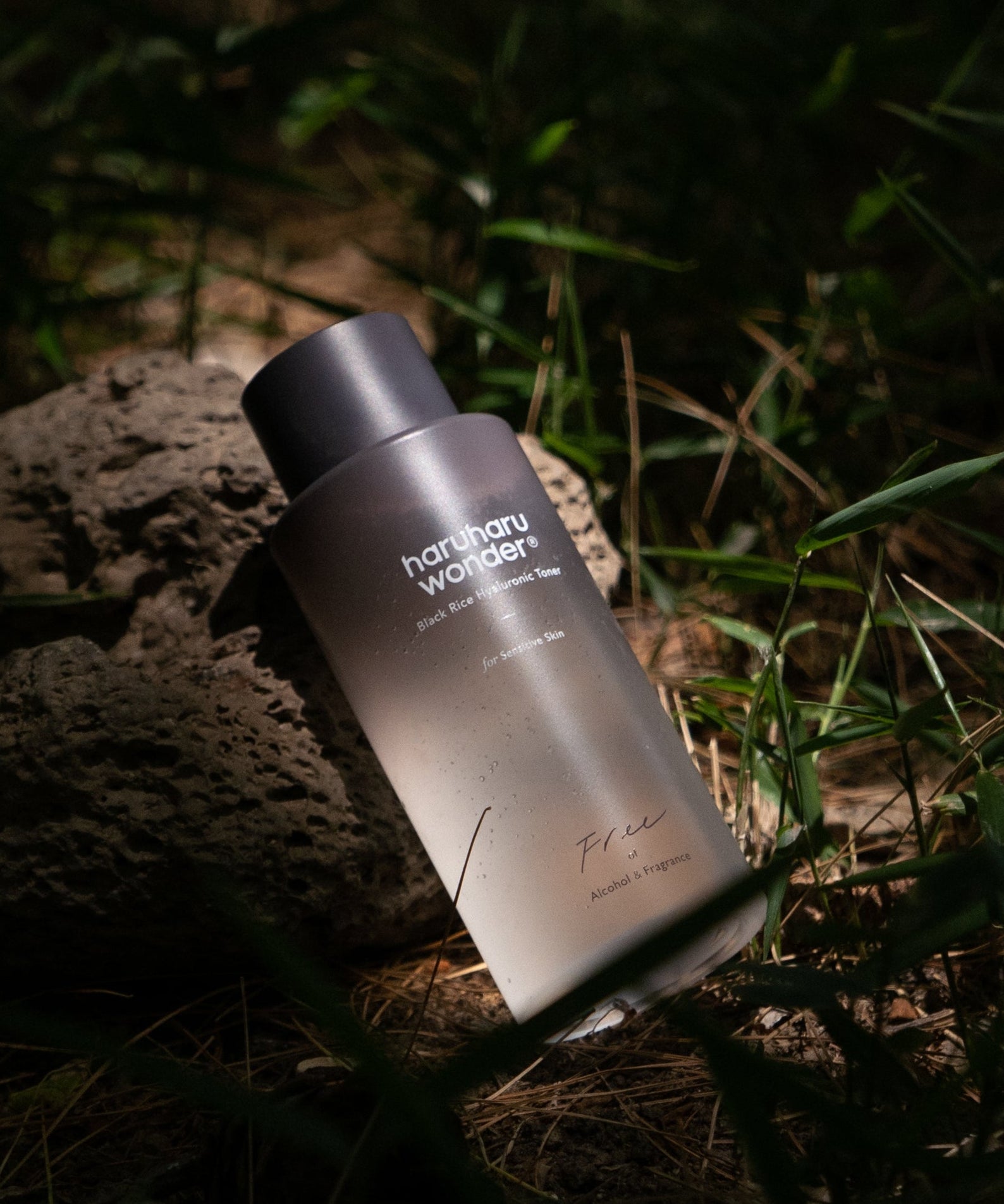 HARUHARU Black Rice Hyaluronic Toner Unscented 150ml de la marque HARUHARU, bouteille sur pierres, dans la nature.