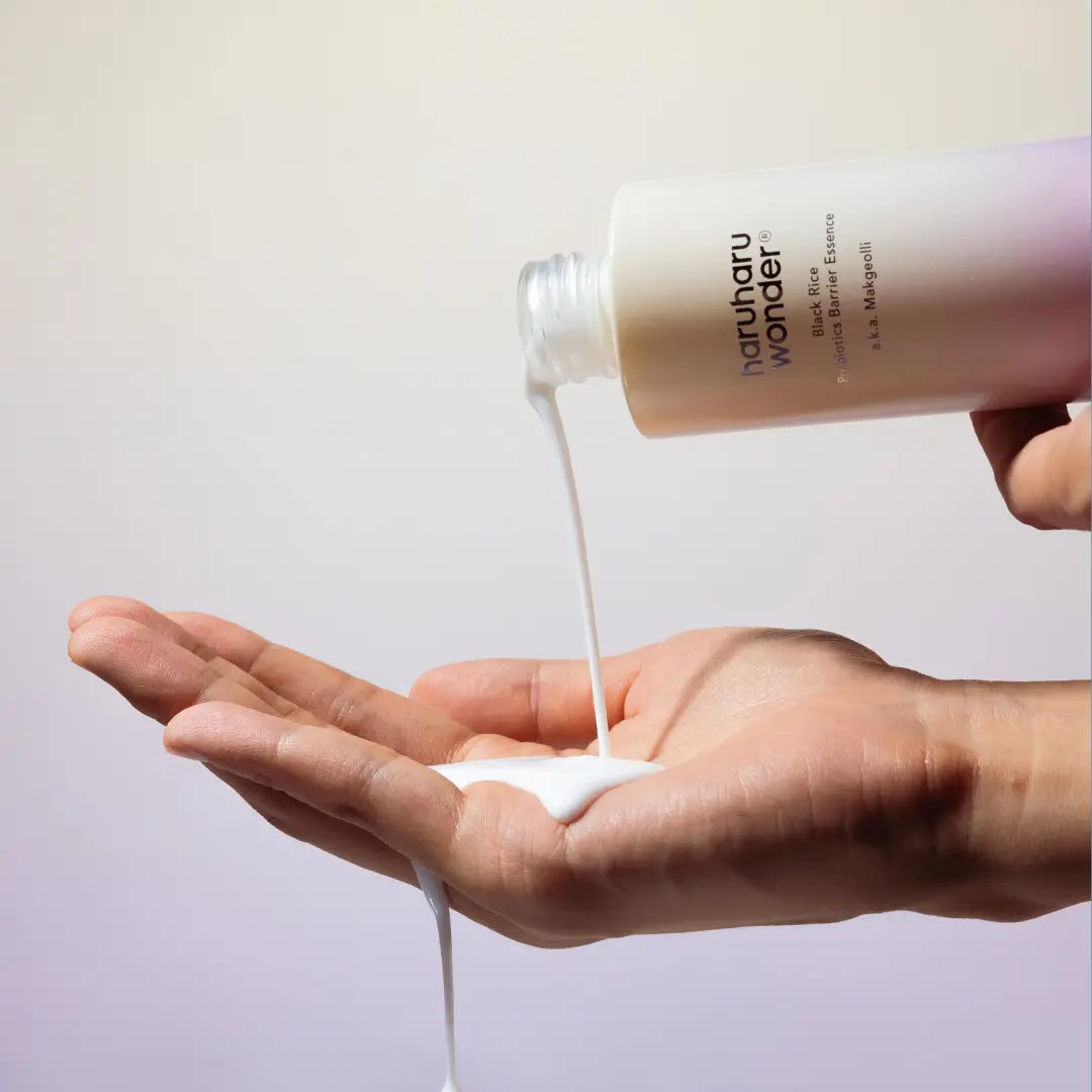 HARUHARU Black Rice Probiotics Barrier Essence 120ml : main recevant le sérum, flacon HARUHARU, fond clair.
