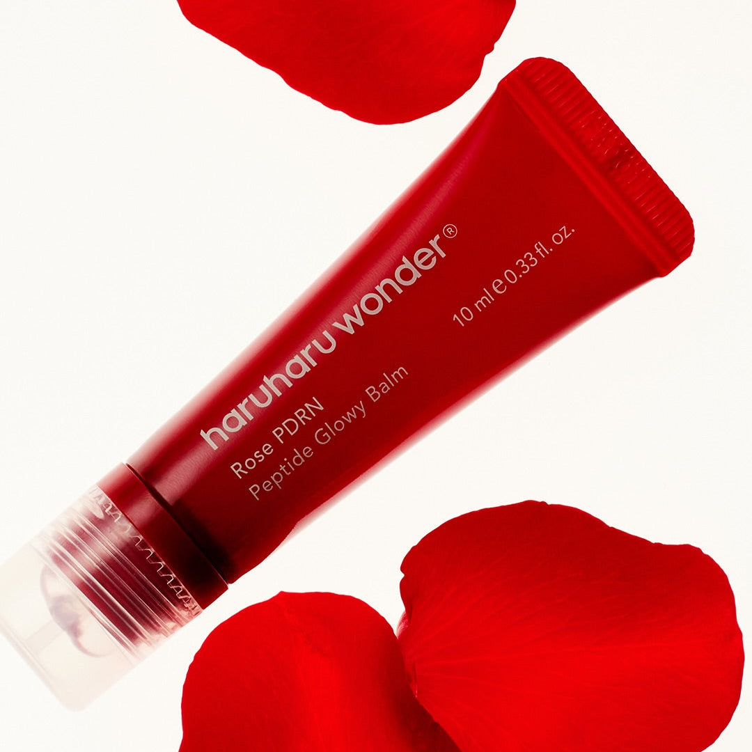 Décris l'image en français : HARUHARU Rose PDRN  Peptide Glowy Balm 10ml, tube rouge et pétales roses sur fond clair.