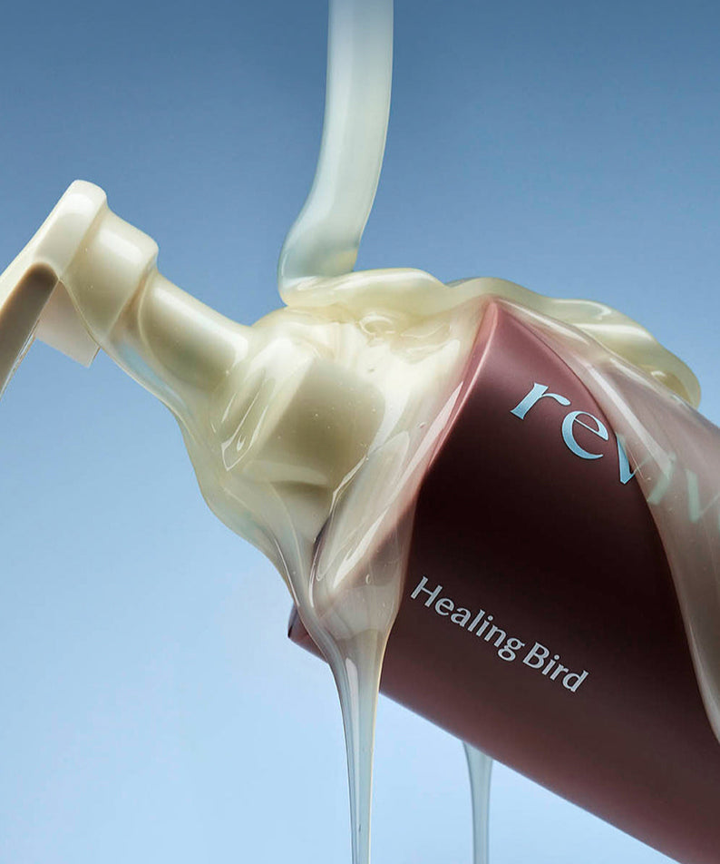 Flacon de HEALING BIRD Revive Protein Shampoo 500ml avec du shampooing coulant, sur fond bleu.