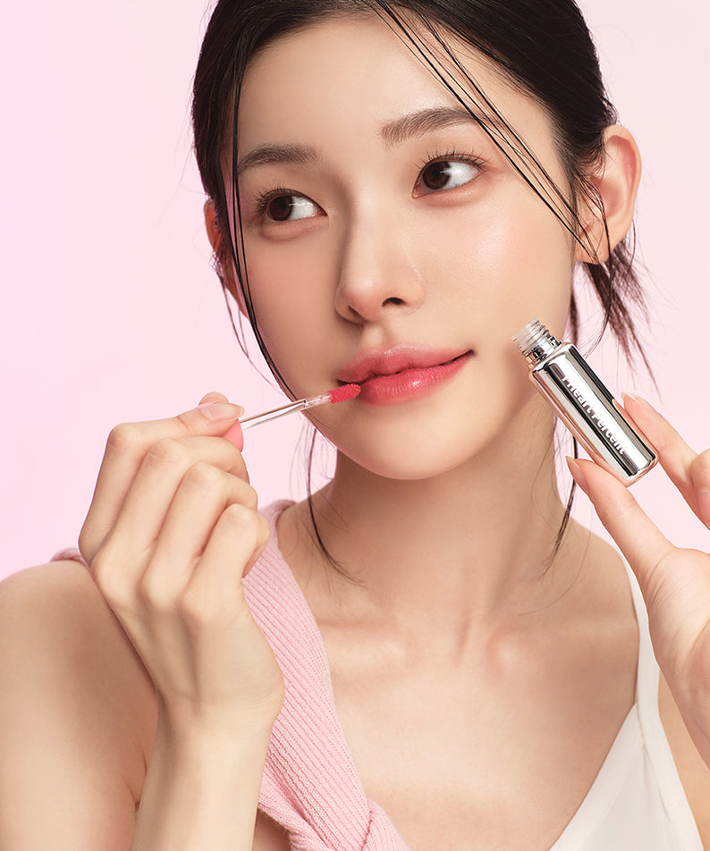 HEART PERCENT Dot On Mood First Tint 3.4g, maquillage sur une femme, tube rose, flacon et application, fond rose.