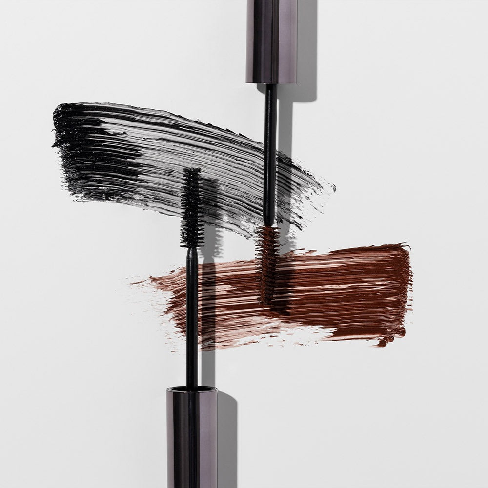 HEIMISH Dailism Mascara de la marque HEIMISH, brosse sur un maquillage aux cils, texture noire sur fond clair.