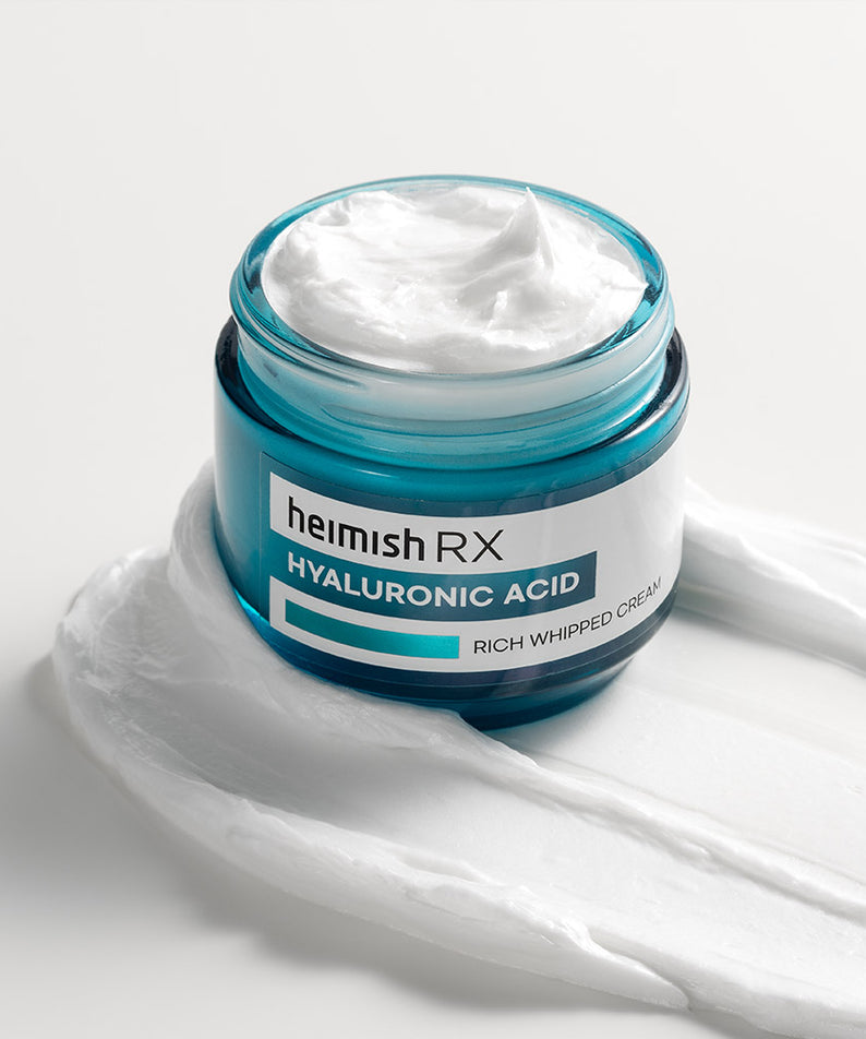 Pot ouvert de HEIMISH RX Hyaluronic Acid Rich Whipped Cream 50ml sur fond blanc avec crème déposée à côté.