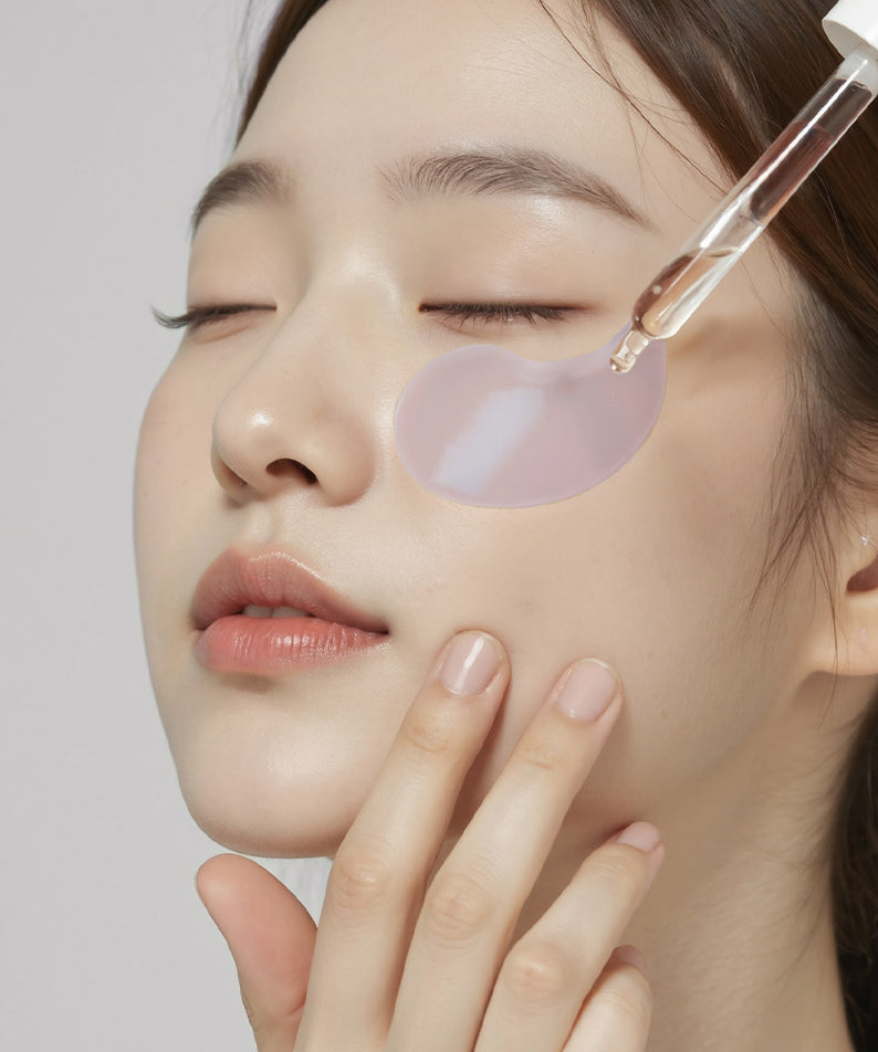 Application des HEIMISH RX Retinol Bakuchiol Hydrogel Eye Patches 60 Sheets sous les yeux d'une femme avec un sérum.