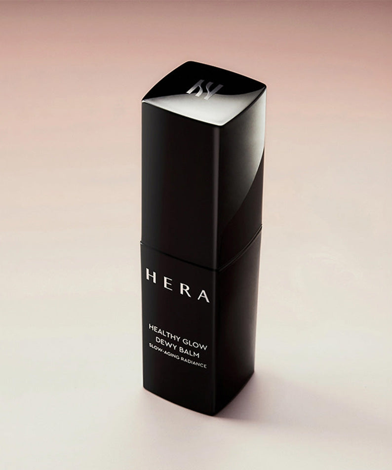 Baume lumineux HERA Healthy Glow Dewy Balm 10g sur fond rose pâle, produit cosmétique pour éclat naturel.