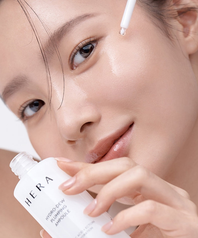 HERA Hydro-Dew Plumping Ampoule 50ml : jeune femme applique le sérum hydratant HERA sur le visage, gouttelette visible