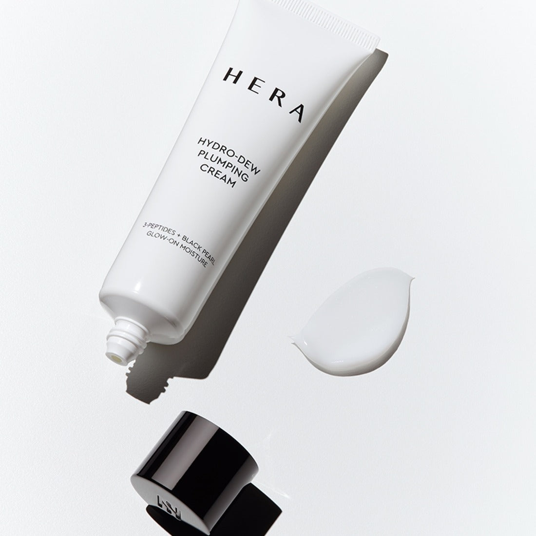 HERA Hydro-Dew Plumping Cream 50ml, crème hydratante HERA en tube blanc sur fond clair, texture et pot échantillon