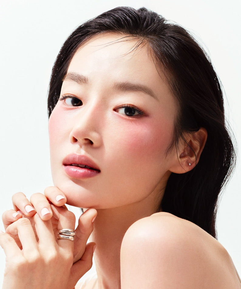 HERA Reflection Liquid Blush 7.5g : gros plan sur le visage maquillé avec touche de blush, style beauté sur fond clair.