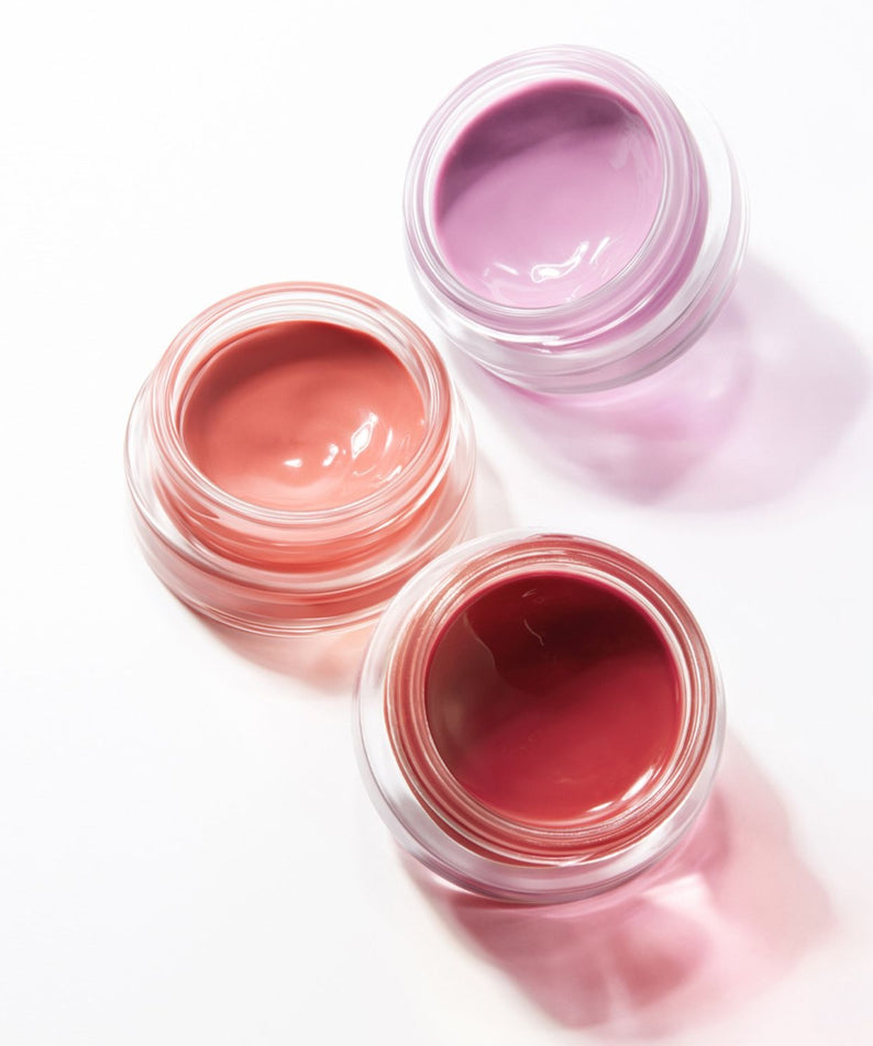 HERA Sensual Lip & Cheek 7g de HERA, pots ouverts de baume lèvres/rouge à joues sur fond clair pastel.