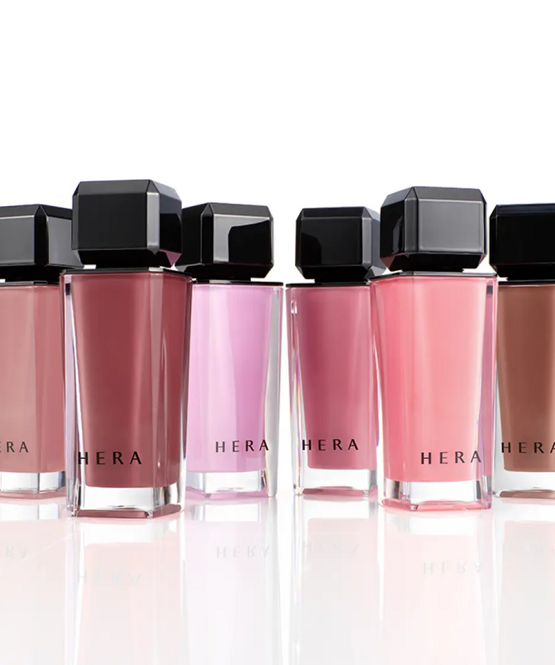HERA  Sensual Nude Gloss 5g : flacons HERA roses et nude sur fond clair, rendu maquillage brillant en studio.