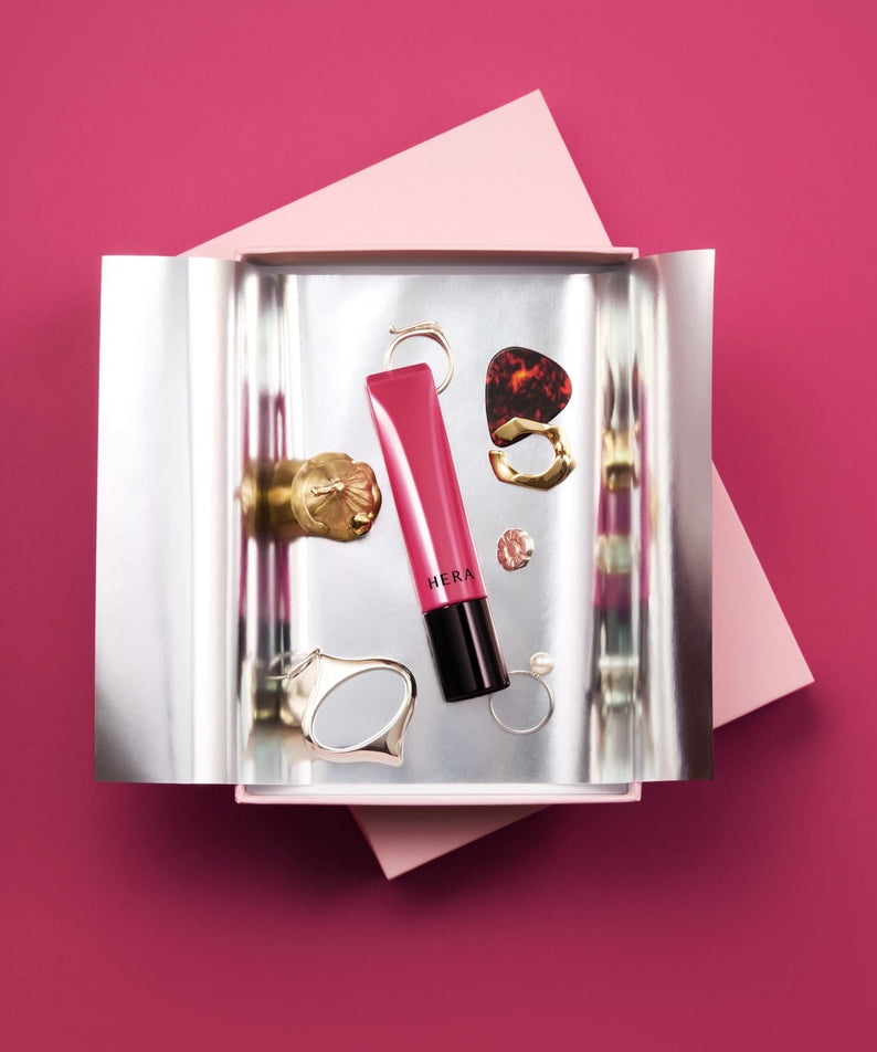 HERA Sensual Tinted Shine Lip Serum 8.5g, en packaging élégant sur fond rose, produit HERA en vue produit.