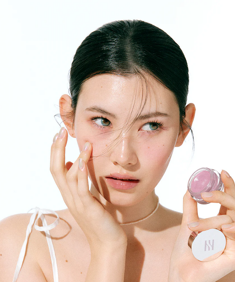 Femme appliquant HERA Sensual Lip & Cheek 7g sur ses joues, maquillage frais et élégant. Focus sur le produit et son utilité polyvalente.