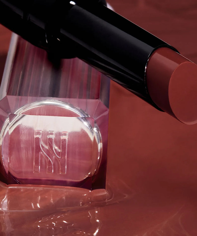 Rouge à lèvres HERA Sensual Tinted Shine Stick 3.5g posé élégamment sur une surface en cuivre brillant.