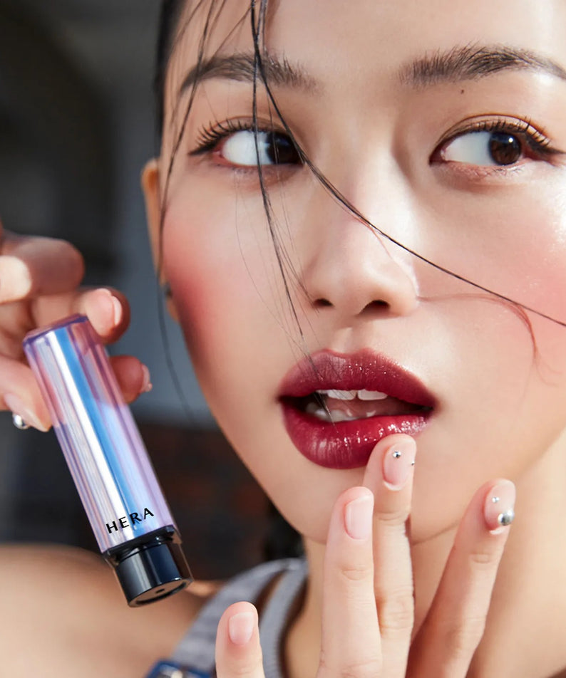 Jeune femme avec HERA Sensual Tinted Shine Stick 3.5g montre un look vibrant et tendance, accentuant ses lèvres avec brillance et couleur.