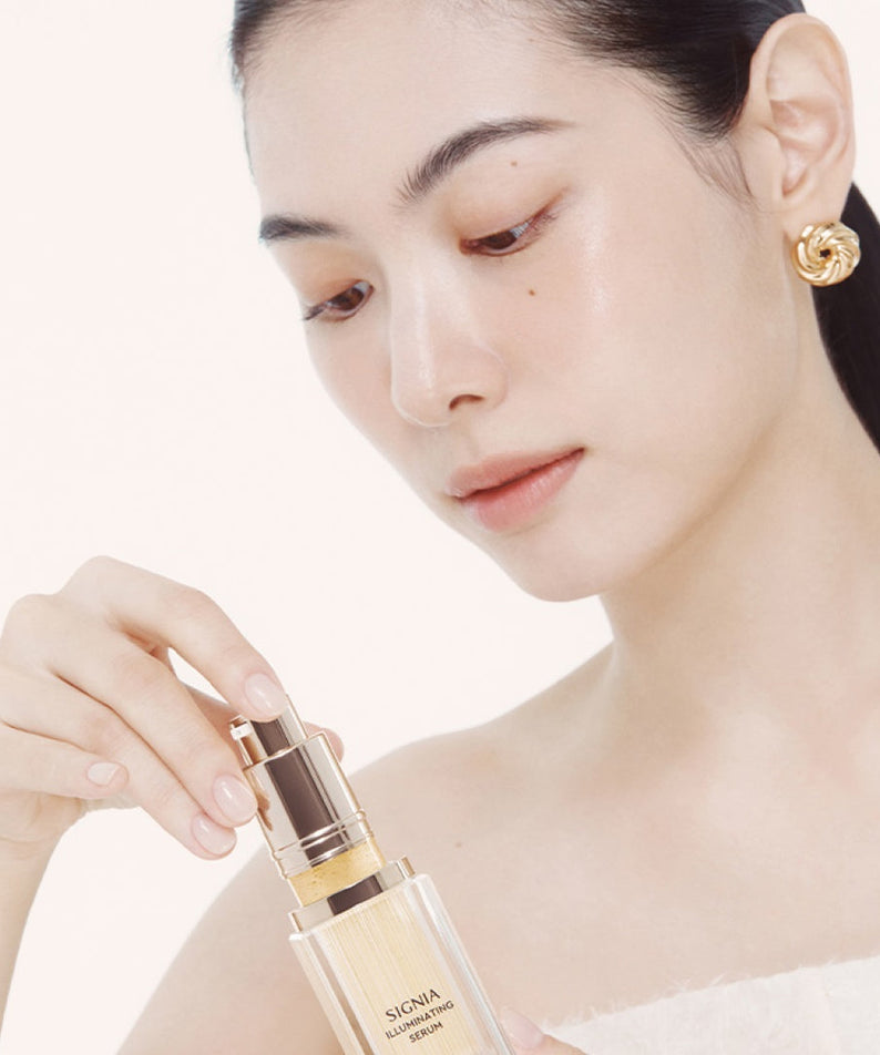 Femme appliquant HERA Signia Illuminating Serum 30ml sur sa peau, soin éclatant pour une peau radieuse.