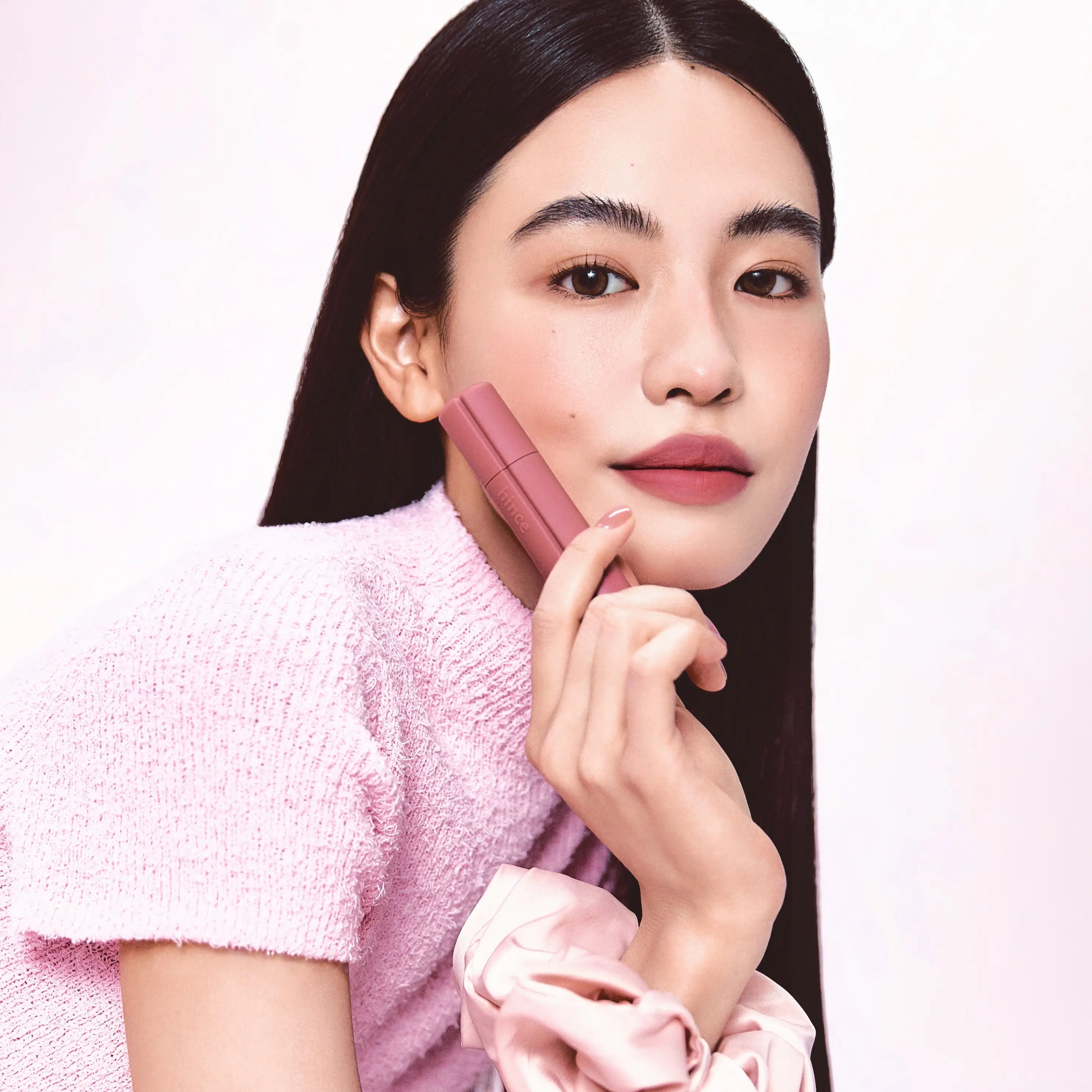 Modèle tenant un rouge à lèvres : HINCE Nouvelle Tint 10 Colors, marque HINCE, fond blanc, portrait maquillage