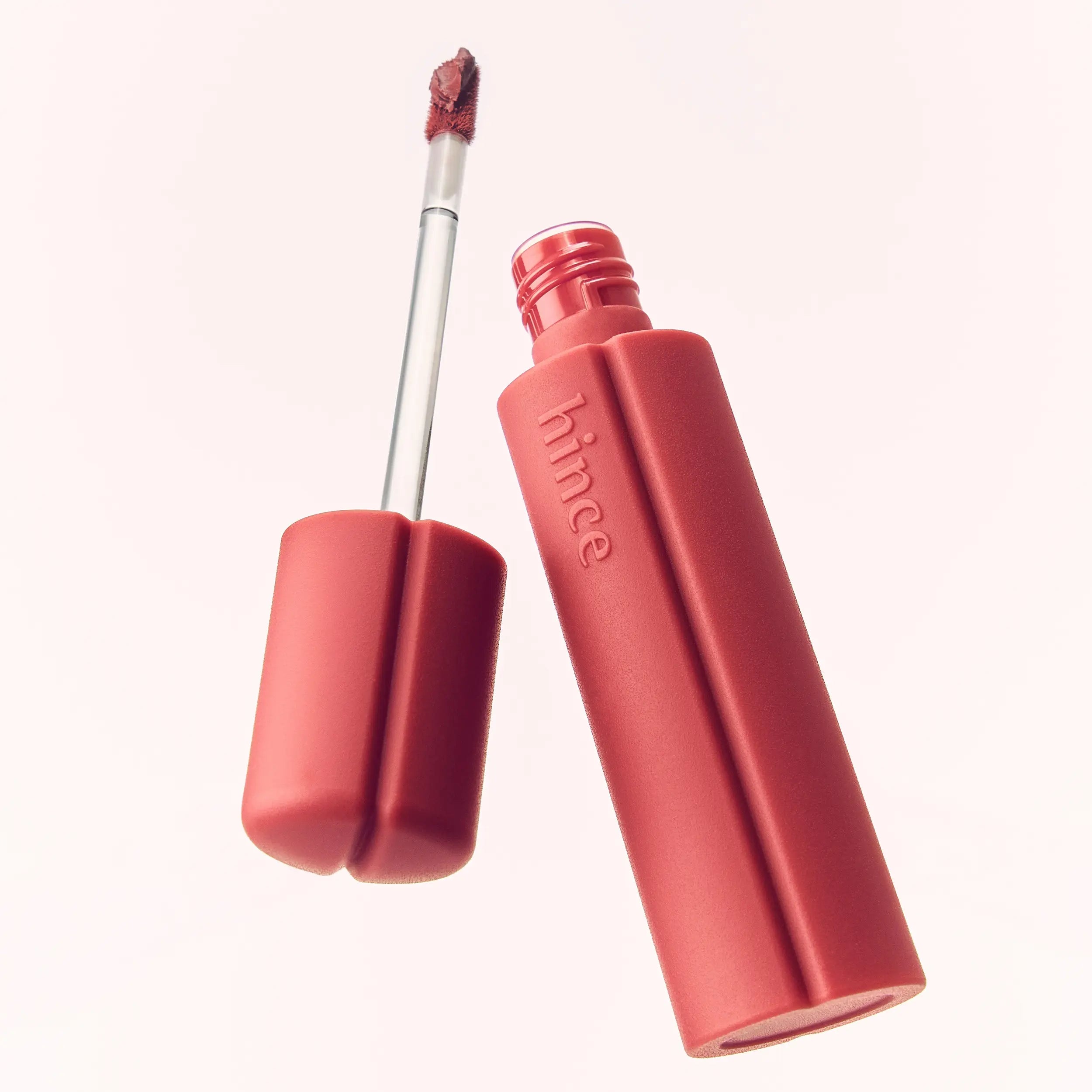 HINCE Nouvelle Tint 10 Colors de HINCE, flacon et applicateur sur fond clair, maquillage lèvres en gros plan.