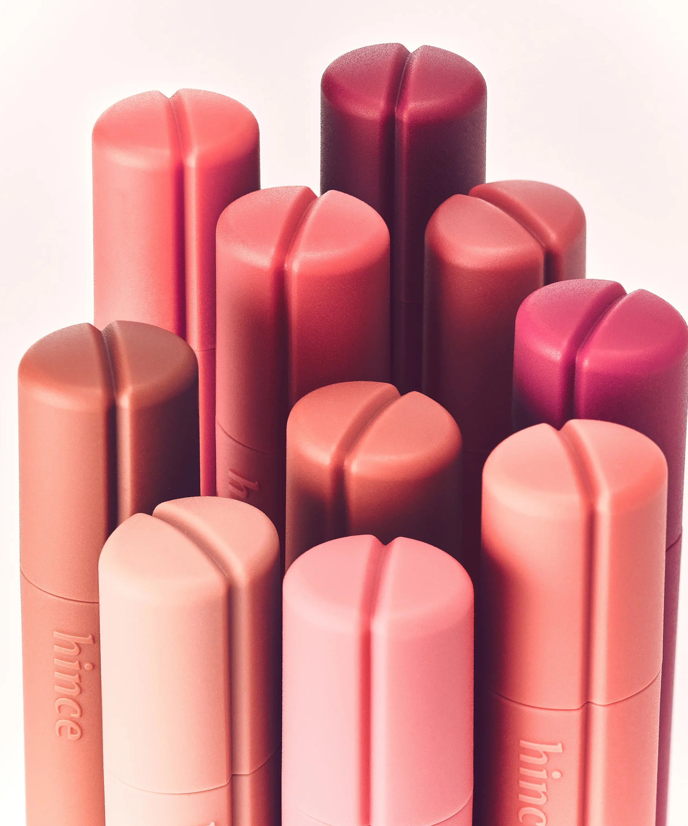 HINCE Nouvelle Tint 10 Colors, baumes à lèvres HINCE rose et rouge sur fond clair, packshot produits.