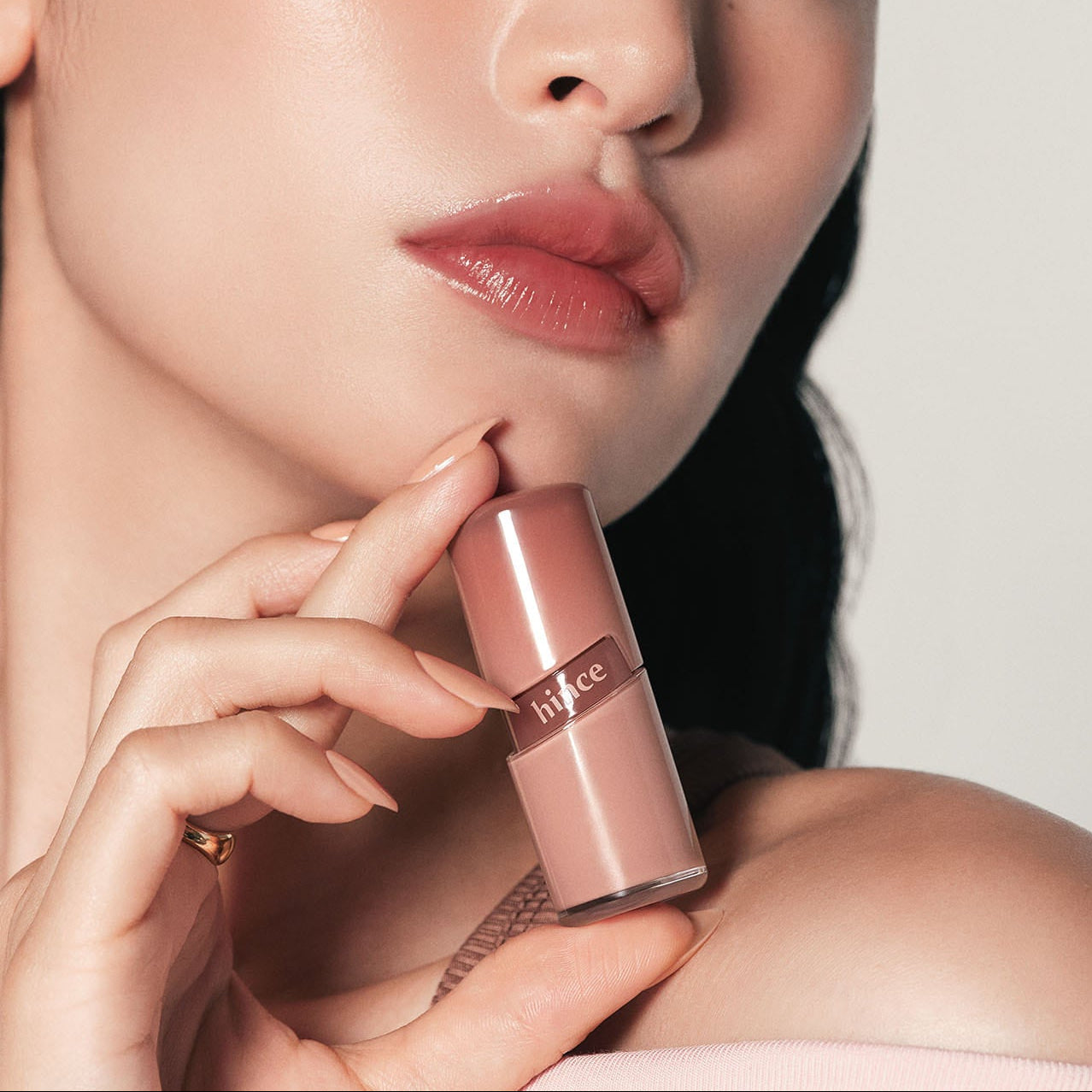HINCE  Raw Glow Gel Tint, femme maquillée appliquant le gel tint sur les lèvres, lumière studio, gros plan