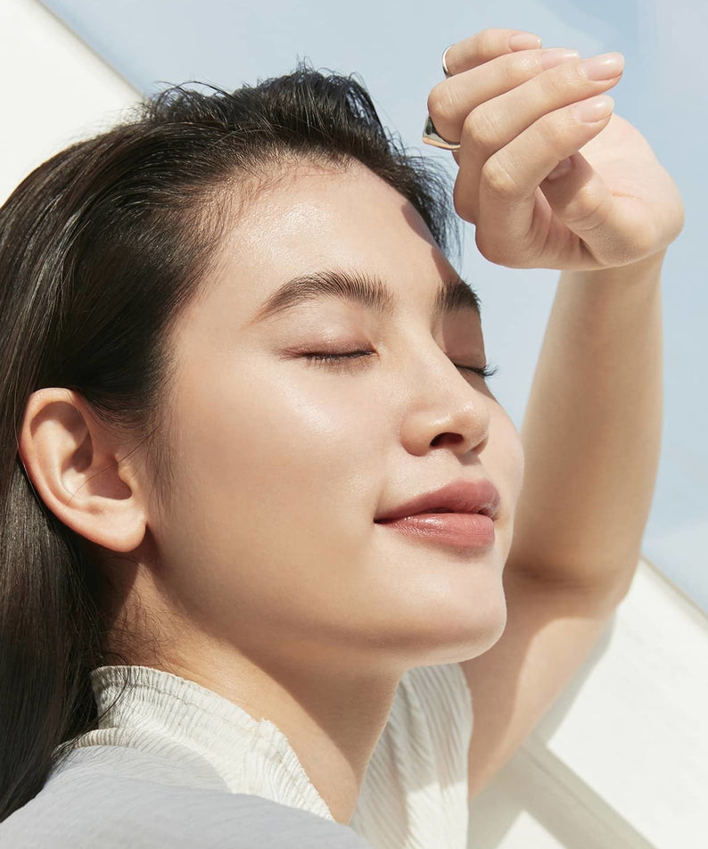 Femme avec peau radieuse utilisant HINCE Second Skin Cover Concealer, exposée au soleil, démontrant un teint naturel et uniforme.