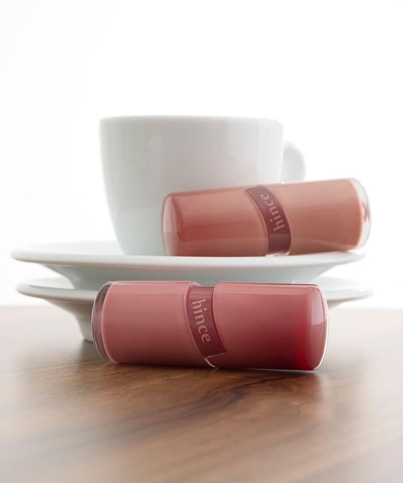 HINCE Low Glow Gel Tint posé devant une tasse blanche, offrant une texture gel élégante et une teinte subtile pour un éclat naturel.