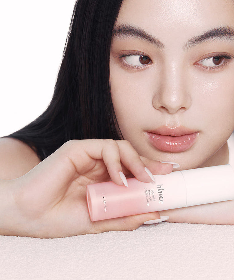 Femme tenant le HINCE Radiance Makeup Boosting Prep 30ml avec un regard lumineux, idéal pour une peau radieuse.