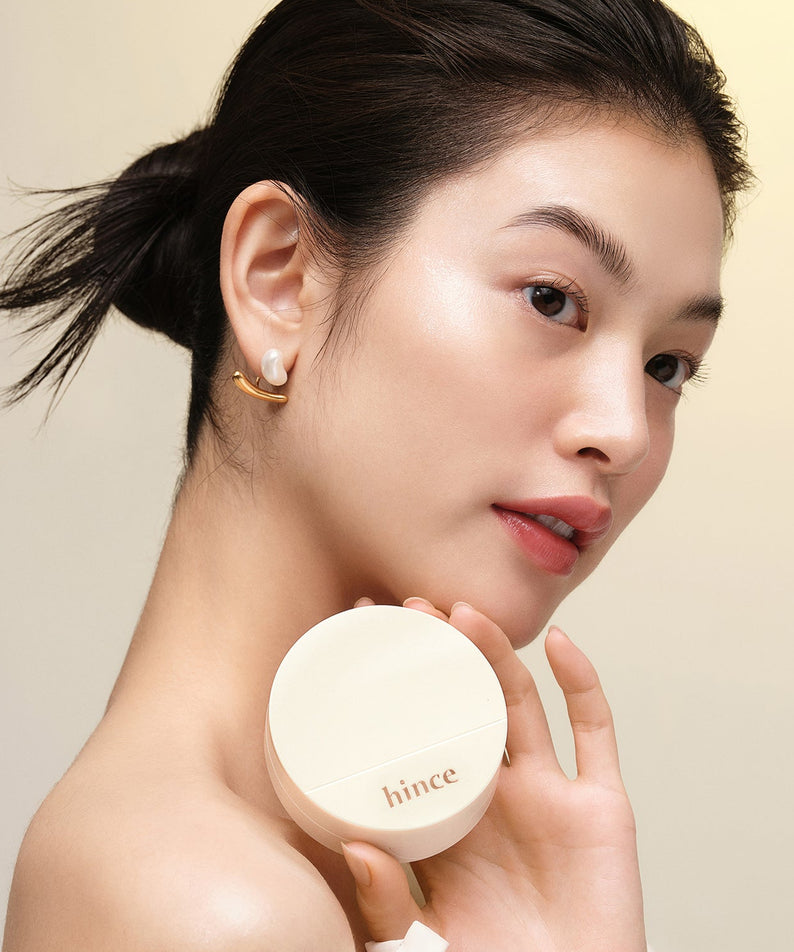 Femme tenant le HINCE Second Skin Glow Cushion avec un éclat naturel sur la peau.