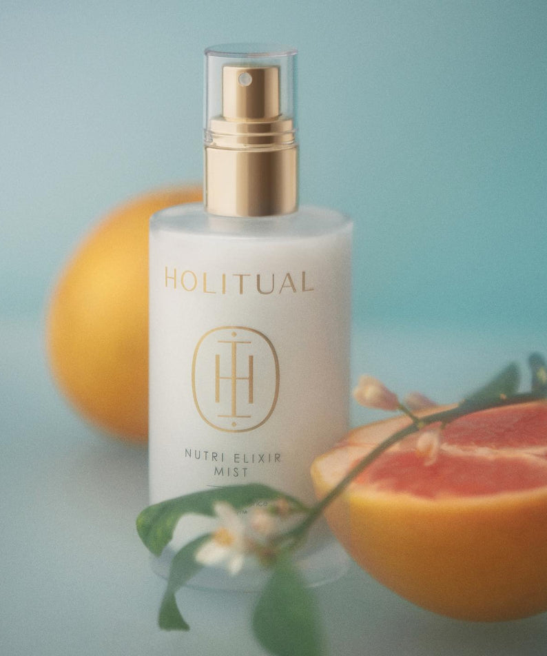 HOLITUAL Elixir Mist 140ml, brume visage en flacon doré sur fond bleu avec agrumes et fleurs, beauté