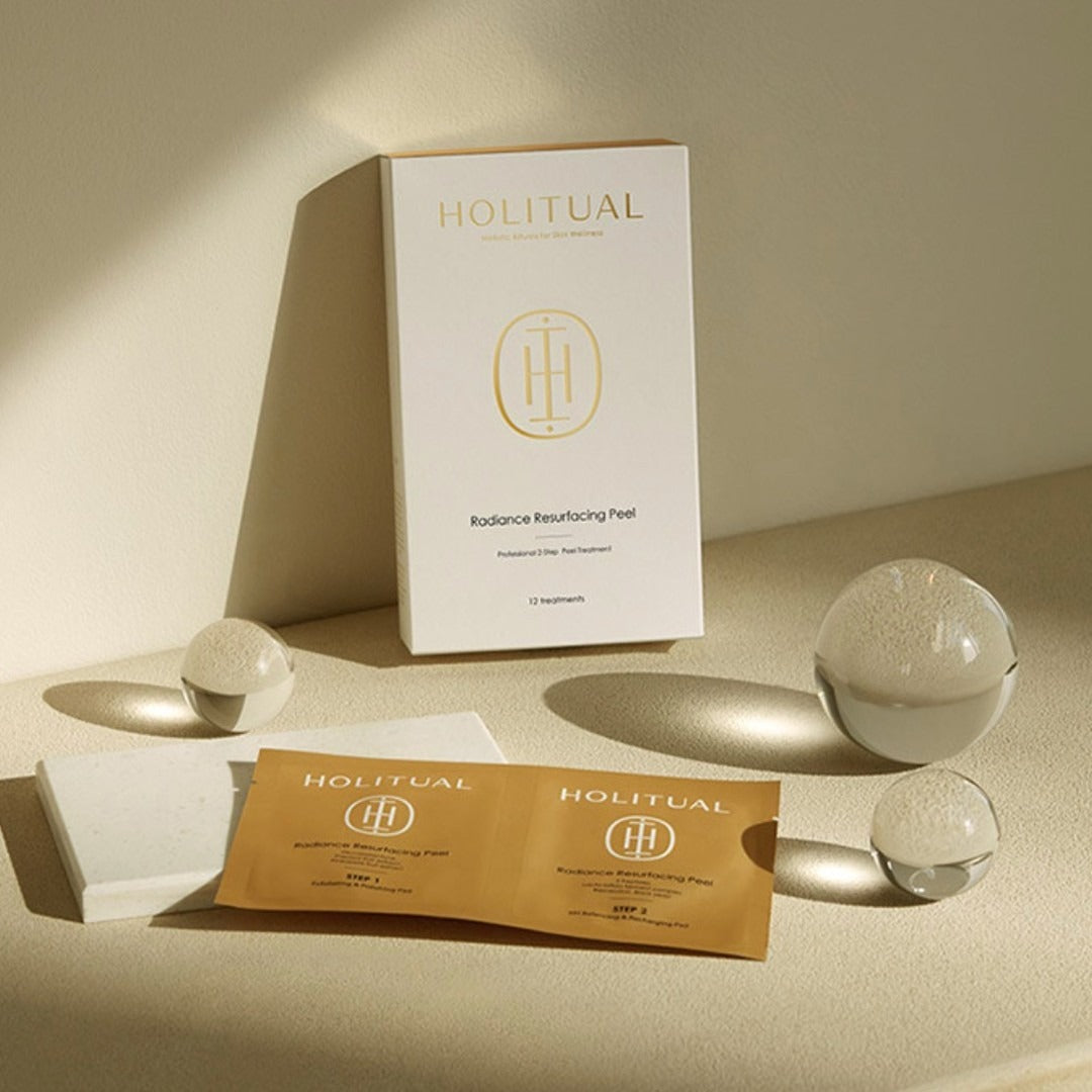 HOLITUAL Radiance Resurfacing Peel de la marque HOLITUAL, coffret et sachets sur table beige, ambiance spa minimaliste.