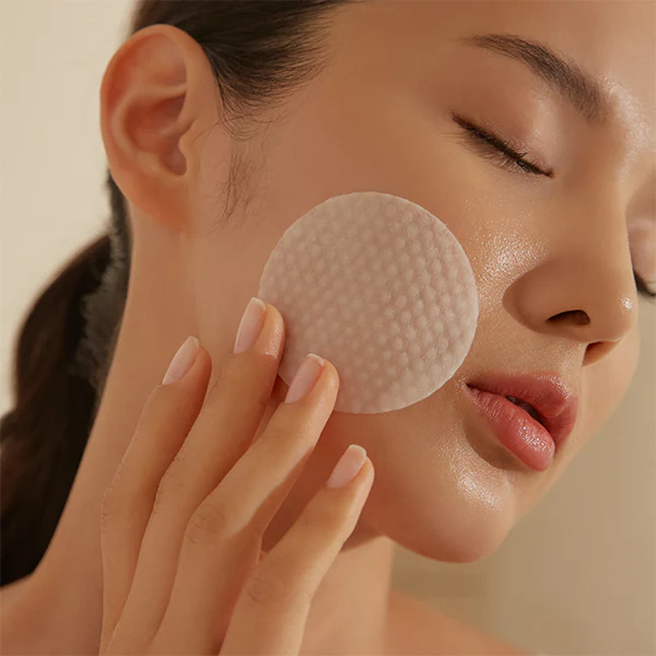 HOLITUAL Radiance Resurfacing Peel : femme applique un soin peel sur le visage, peau éclatante, ambiance beauté.