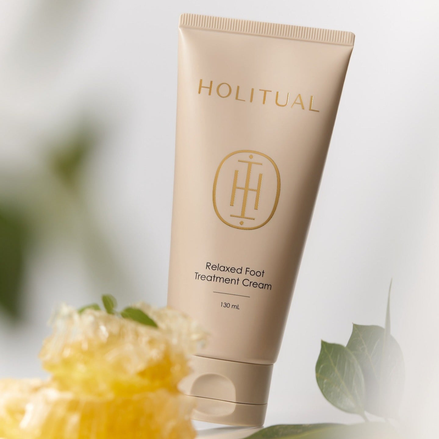 HOLITUAL Relaxed Foot Treatment Cream 130ml, tube beige sur fond clair avec feuilles vertes et fleurs, vue produit.