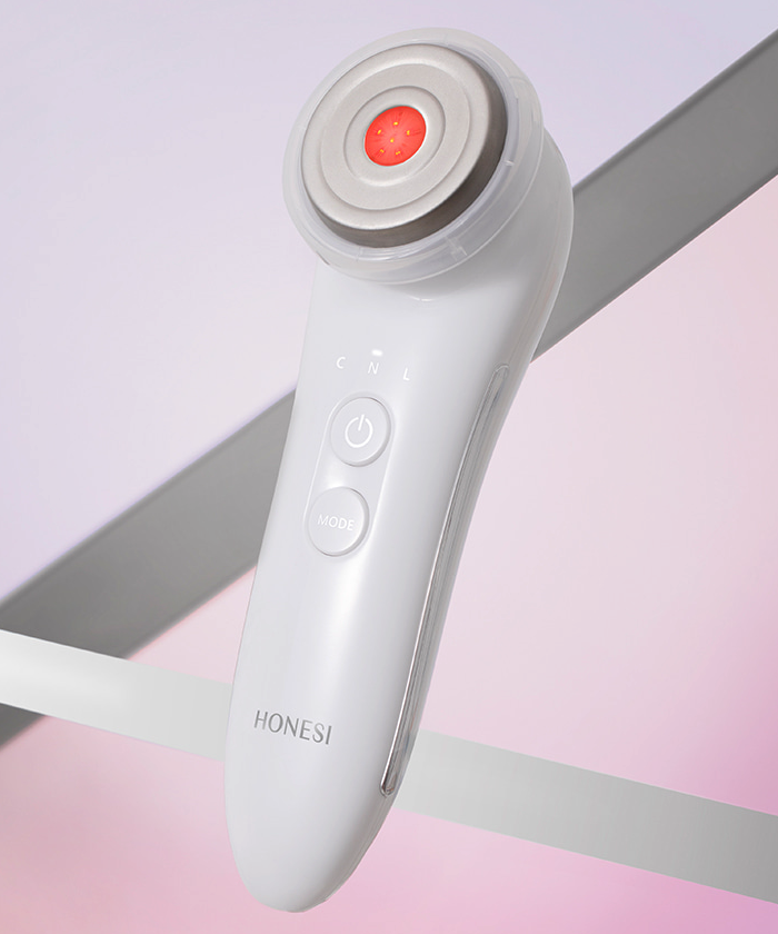 Décris l'image en français : HONESI  EMS High Frequency Galvanic Home Care Massager, appareil de soins visage, en blanc sur fond rose.