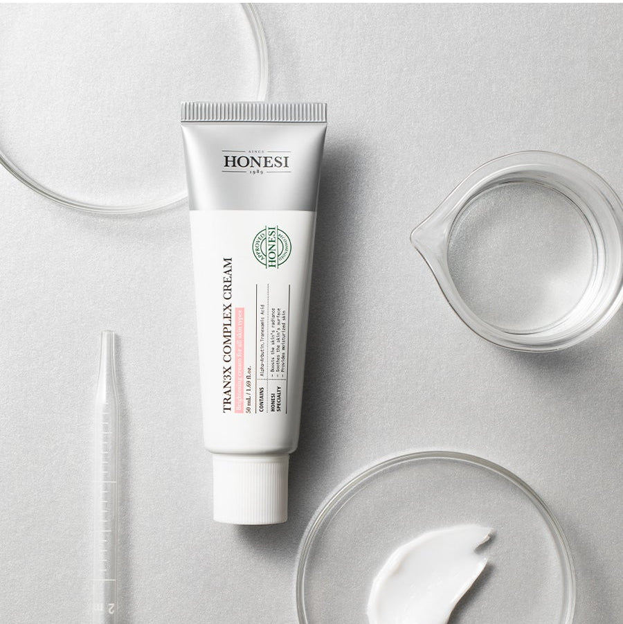 HONESI  Tranex Complex Cream 50ml, tube crème sur fond blanc minimal, flacon et texture de crème, photo produit