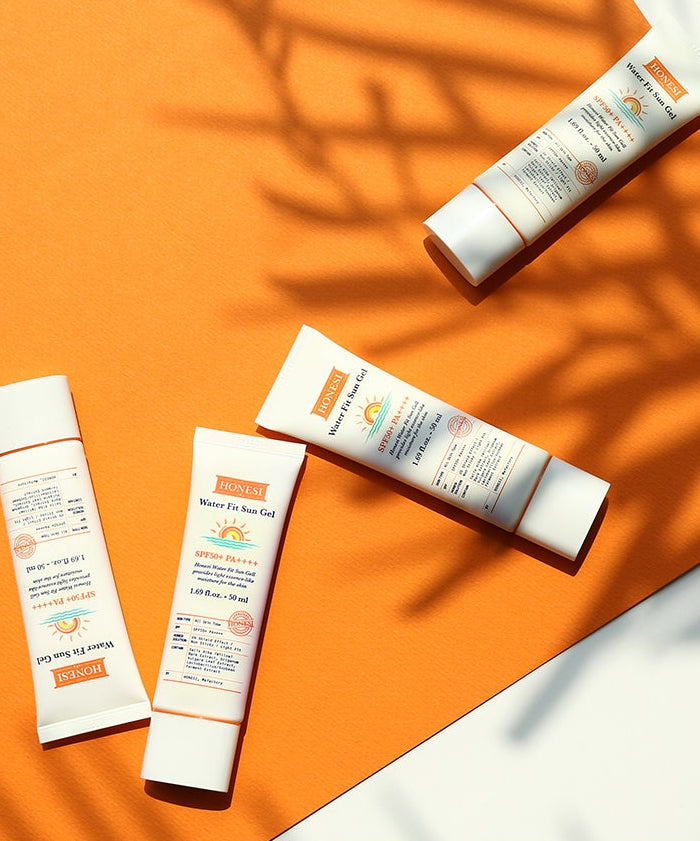 HONESI  Water Fit Sun Gel 50ml de la marque HONESI, tubes de crème solaire sur fond orange ensoleillé, ombres