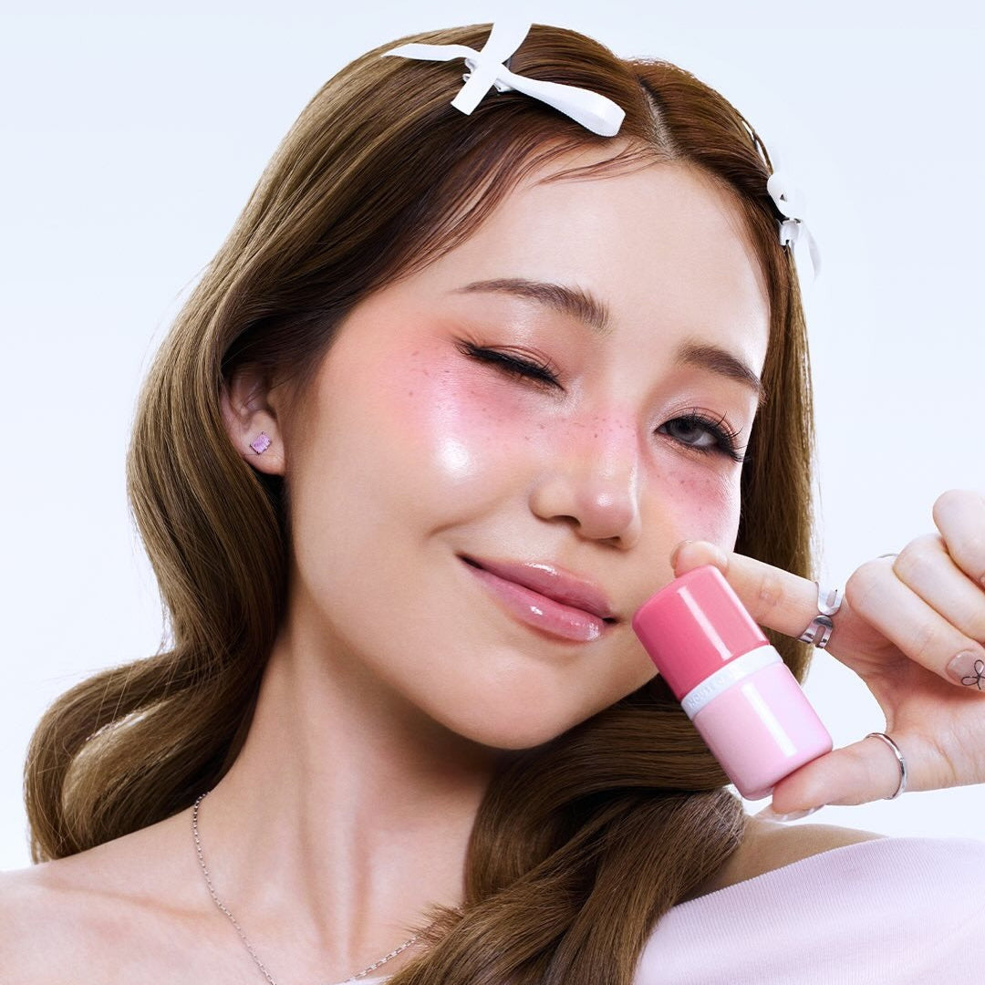 HOUSE OF HUR Every Cheek Blush : femme applique un blush rose, maquillage lumineux sur fond clair (marque HOUSE OF HUR).