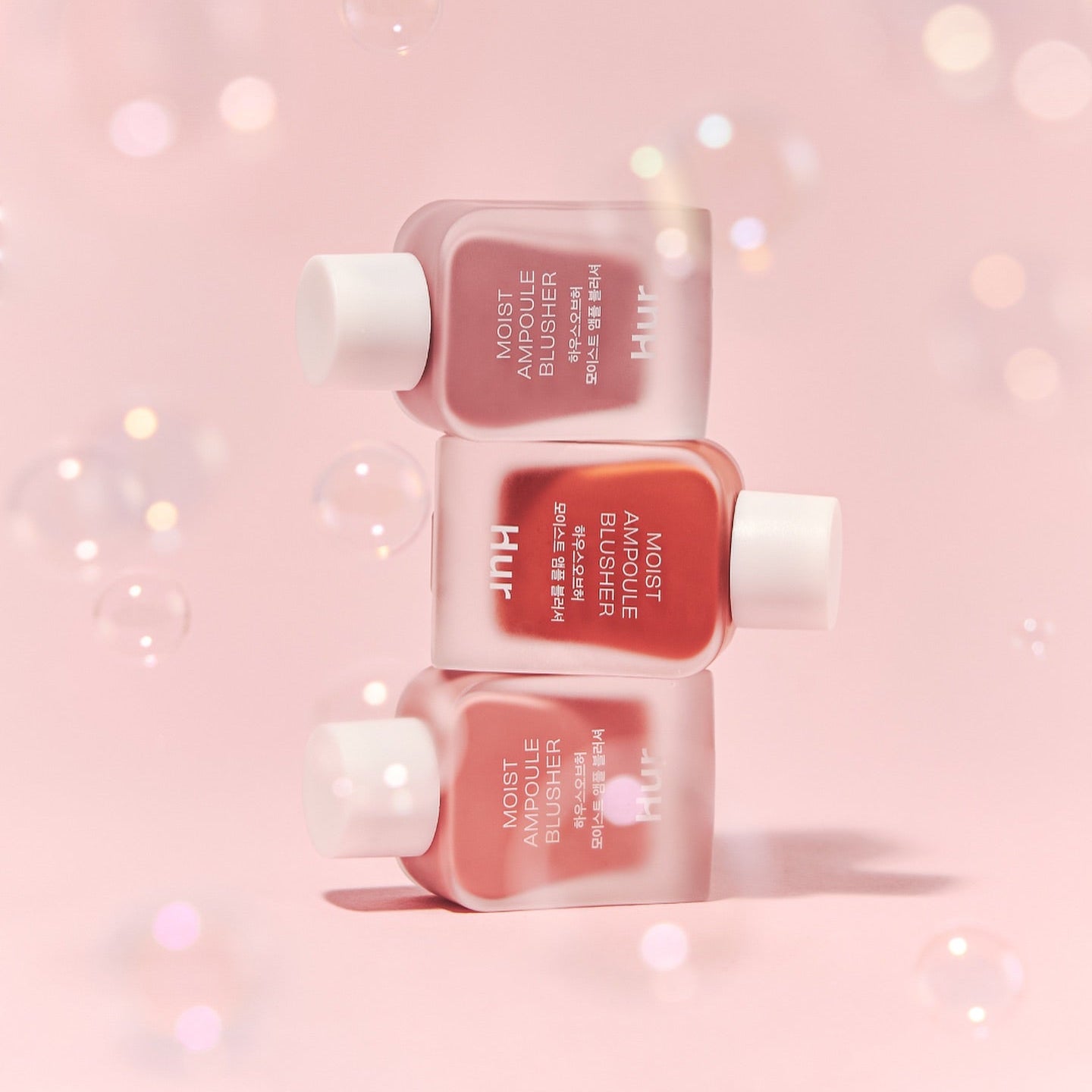 HOUSE OF HUR Moist Ampoule Blusher 10ml de la marque HOUSE OF HUR, flacons roses sur fond rose pailleté, maquillage.