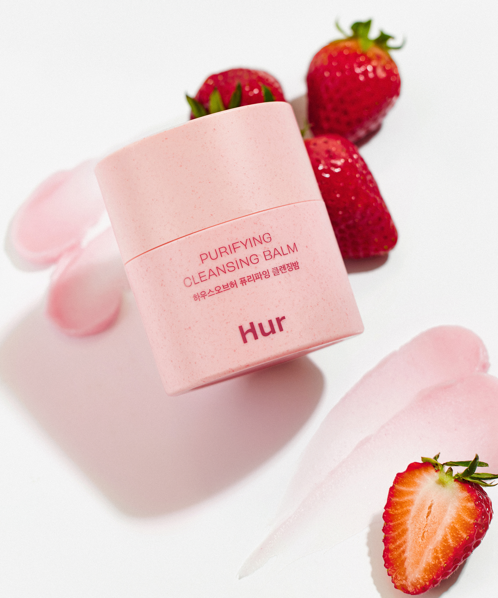 HOUSE OF HUR Purifying Cleansing Balm, pot rose sur fond blanc avec fraises; cosmétique visage nettoyant.
