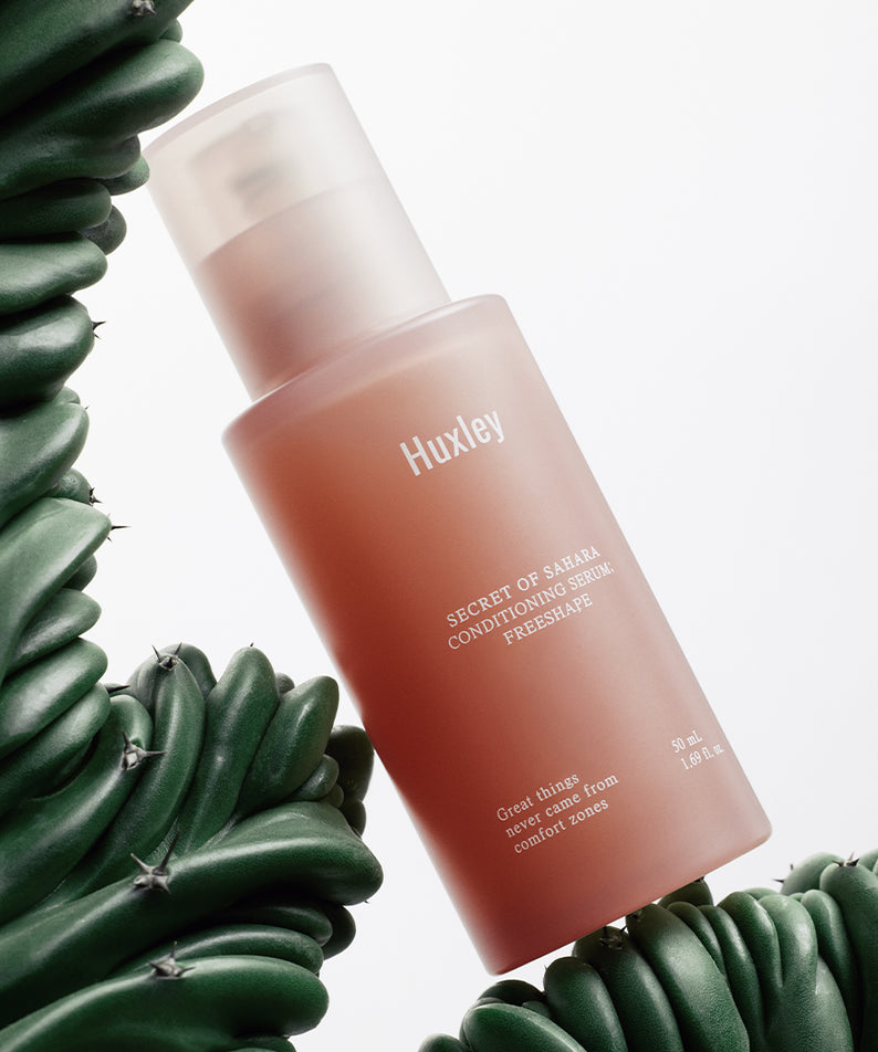 Sérum HUXLEY Conditioning Serum Preshape exposé avec un cactus, soin de peau novateur et hydratant.